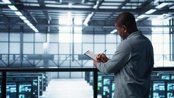 Cheerful admins meeting in data center to review reports and files, doing handshake. Server room employee saluting colleague, doing troubleshooting to prevent downtime, camera B video