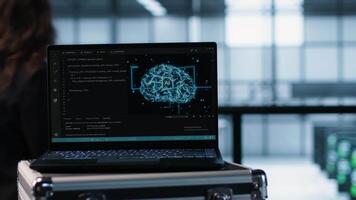 Laptop in front of data center engineers in blurry background deploying artificial intelligence driven management tools. AI driven notebook used for overseeing server clusters, camera A close up video