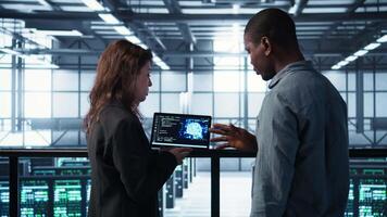 Software developers in data center use AI technology on tablet to optimize storage volumes. IT specialists in server hub facility using artificial intelligence to ensure seamless operations, camera B video