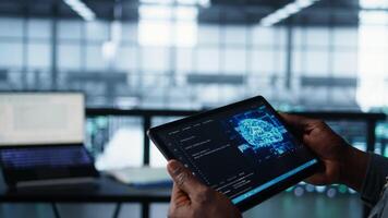 Programmer in data center using AI tech on tablet, testing equipment failover scenarios. Server farm IT specialist uses artificial intelligence on device, ensuring data accessibility, camera B closeup video