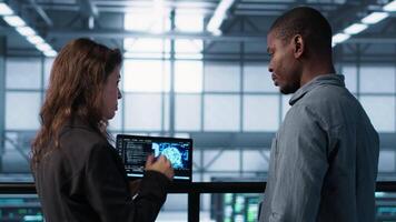 Software developers in data center use AI technology on tablet to optimize storage volumes. IT specialists in server hub facility using artificial intelligence to ensure seamless operations, camera A video