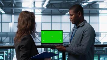 Engineering team in data center using green screen laptop, implementing predictive analytics scripts, reviewing equipment health, adjusting system parameters, coordinating maintenance tasks, camera A video