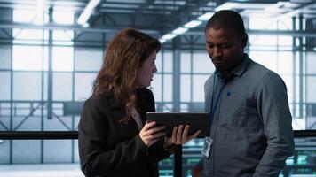 Computer scientists in data center using tablet to develop disaster recovery plans. IT professionals in server farm discussing, testing failover scenarios, protecting data during disruptions, camera A video