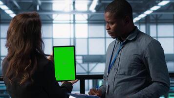 Engineers using green screen tablet in data center, checking infrastructure reliability, writing in clipboard. Workers using mockup device in server room, managing server virtualization, camera A video