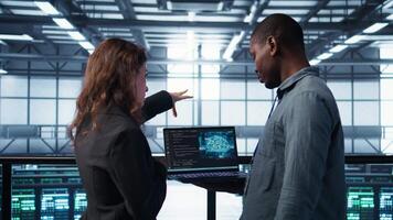 Software developers in data center using laptop, employing AI machine learning models. Workers using notebook to fulfill artificial intelligence infrastructure needs, allocating resources, camera B video