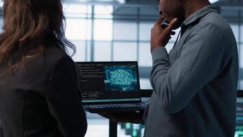 Software developers using AI tech on laptop in data center managing server virtualization. IT expert coding on notebook in server room using artificial intelligence, finetuning network, camera A video