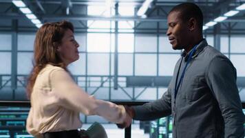 Data center engineer greeting colleague, examining system diagnostics paperwork together. Server room workers doing handshake, meeting to look over maintenance reports, camera A video