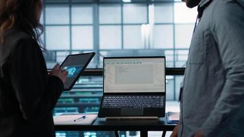 Programmers using AI technology on laptop and tablet in data center employing machine learning models. Devices used by artificial intelligence IT experts in server farm, camera A video
