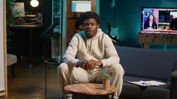 Black male student trying to learn a new language from his living room, attending an online course lesson to develop his skills. Ambitious person solving exercises and tasks remotely. Camera A. video