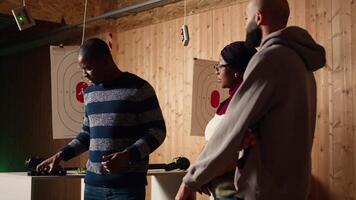 Shooting gallery safety officer demonstrating how to safely reload pistol and gun to clients, supervising range activities. Firing range expert teaching proper weapon handling and usage, camera A video