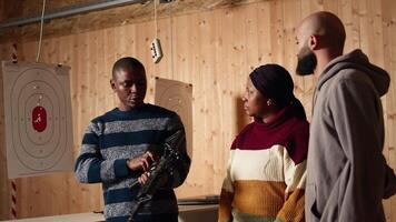 Shooting range safety officer demonstrating how to safely reload semiautomatic weapon to customers, ensuring they follow rules. Firing range employee teaching proper assault rifle handling, camera A video