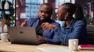 Young couple doing teamwork and multitasking on laptop at desk, fully connected to the internet while managing freelance work and remote responsibilities. Browsing web at home. Camera B. video