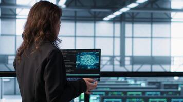 AI technology used by data center software developers reviewing equipment diagnostics. Programmers coding on laptop using artificial intelligence, adjusting server farm configurations, camera A video