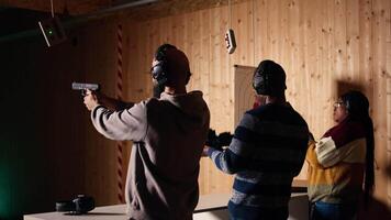Friends in firing range doing recreational shooting, pressing mechanism to recall paper targets. People training with handguns, sharpening skills, checking points scored on bullseyes, camera A video