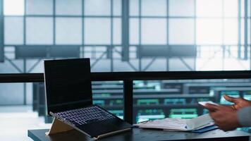 Technician in data center with laptop and tablet integrating AI driven automation tools. Server room worker using artificial intelligence on devices, ensuring continuous uptime, camera A video