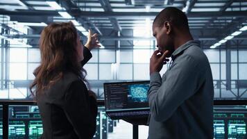 Software developers using AI tech on laptop in data center managing server virtualization. IT expert coding on notebook in server room using artificial intelligence, finetuning network, camera B video