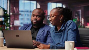 Black freelancers team at home desk using laptop and checking emails, reading messages in inbox and solving their daily tasks. Couple managing electronic correspondence. Camera B. video