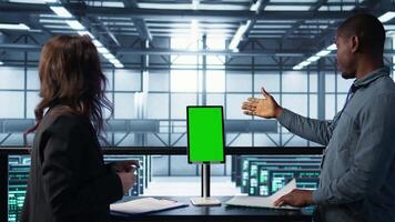 Inspector checking documents in server hub to ensure compliance with industry standards, using mockup tablet. Admin team inspecting files, overseeing data center workplace security protocols, camera B video
