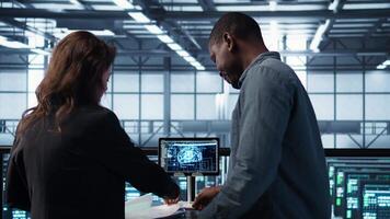 Manager meeting with client in data center to review files, doing handshake after finalizing deal. Server room supervisor reaching agreement with customer after checking documentation, camera B video