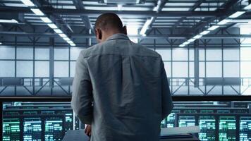 Engineer in data center coding on laptop, optimizing resource utilization, adjusting power management settings. Server room worker maintaining stable infrastructure using notebook, camera B video