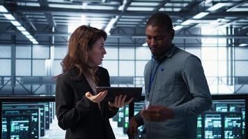 Computer scientists in data center using tablet to develop disaster recovery plans. IT professionals in server farm discussing, testing failover scenarios, protecting data during disruptions, camera B video