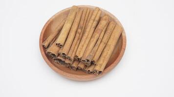Heap of Dried Cinnamon Spice on Wooden Plate on White Background photo