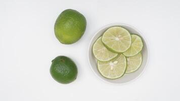 Slices Green Lime Fruit on Bowl on White Background photo