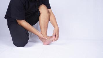 Man Holding Foot Suffering from Leg Cramp on White Background photo