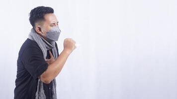 Side View of Young Asian Man Wearing Mask Coughing on White Background photo