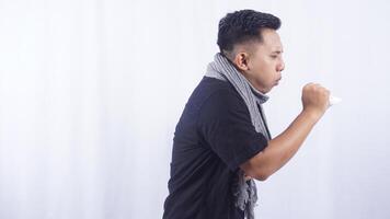Young Asian Man with Scarf Having Cold and Cough on White Background photo