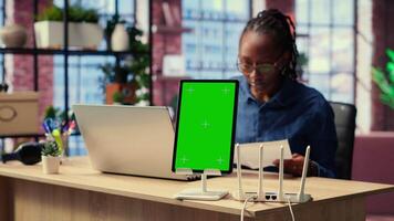 Black girl tries to fix an Wi Fi error by rebooting router next to isolated screen, troubleshooting signal loss problems to solve technical issues. Testing different configurations. Camera B. video