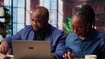 African American couple discusses mortgage and insurance payments at home, using calculator to do their household budgeting and money management. Ensuring a secure financial future. Camera B. video
