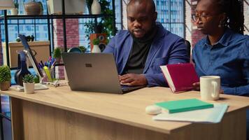 Woman completing spreadsheets on notebook, entering numerical data into cells, calculating totals. African american couple analyzing online information for an accounting task. Camera A. video