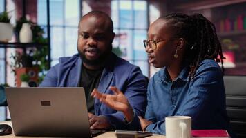 Black couple managing their self employed business finances and taxes, tracking expenses and income while they work remotely from their loft. Doing tax calculations for a debt free year. Camera B. video