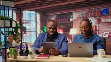Smiling freelancers browsing the web on devices in a modern apartment, demonstrating a lifestyle of independence, connection and productivity in a virtual workspace. Multitasking. Camera A. video