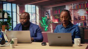 African American man and woman sit at a stylish home office, brainstorming ideas for their digital business, using modern technology to improve communication and project efficiency. Camera A. video