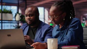 Worried African American woman looks at tax numbers on documents while her partner reassures her, helping with financial planning. Discussing ways to reduce expenses, save money. Camera B. video