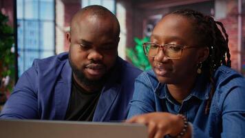 Black man and woman creating a report with online data from archived files, improving their skills and achieving career independence. Remote workers solving daily tasks. Camera A. video