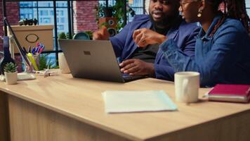 Young couple doing teamwork and multitasking on laptop at desk, fully connected to the internet while managing freelance work and remote responsibilities. Browsing web at home. Camera A. video