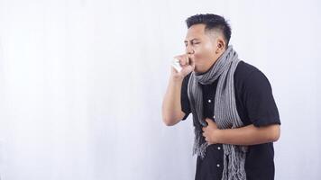 Portrait of Young Asian Man with Scarf Holding Tissue Paper Suffering from Cough on White Background photo