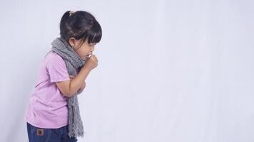 Side View of Unhealthy Asian Little Girl with Scarf Coughing on White Background photo
