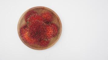 Raw Rambutan Fruit on Wooden Plate on White Background photo