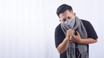 Young Man Wearing Mask Suffering from Cough on White Background photo
