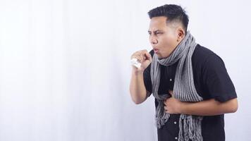 Young Asian Man with Scarf Suffering from Acute Cough on White Background photo