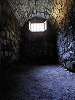 Medieval dungeon with stone walls and a small hatch photo