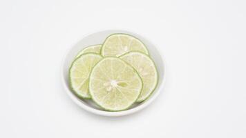 Slices Green Lime on Bowl on White Background photo