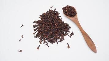 Scattered Dried Cloves with Wooden Spoon on White Background photo