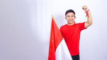 Indonesian Man with Red and White Attribute Showing Yes Pose to Celebrate Independence Day of Indonesia on White Background photo