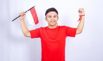 Portrait of Excited Indonesian Man with Red and White Ribbons Showing Yes Gesture Celebrate Independence Day of Indonesia on White Background photo