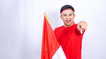 Indonesian Man Pointing to Camera while Holding Red and White Indonesia Flag on White Background photo